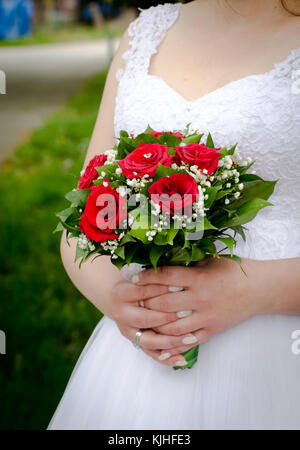 beautiful bride's red roses bouquet in hands of the bride Stock Photo