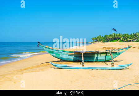 Old wooden oruwa boat of the local fishermen on the scenic sand beach on Bentota, Sri Lanka. Stock Photo
