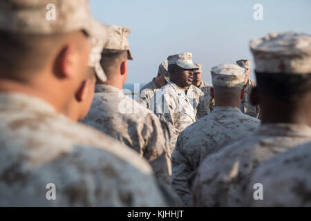 U.S 5TH FLEET AREA OF OPERATIONS (NOV. 08, 2017) Marine Corps 1st Sgt. Meshach Barkley, a native of Quincy, Florida, assigned to the 15th Marine Expeditionary Unit (MEU) embarked aboard the amphibious dock landing ship USS Pearl Harbor (LSD 52), gives a motivational speech on the ship’s flight deck before a ceremony celebrating the 242nd birthday of the Marine Corps. Pearl Harbor is deployed in the U.S. 5th Fleet area of operations in support of maritime security operations designed to reassure allies and partners, and preserve the freedom of navigations and the free flow of Stock Photo