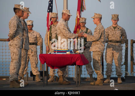 U.S 5TH FLEET AREA OF OPERATIONS (NOV. 08, 2017) Marine Gunnery Sgt. Edgar Estrada (center left) passes the ceremonial first piece of cake to Lance Cpl. Adrian Preciado (center right), both assigned to the 15th Marine Expeditionary Unit (MEU) embarked aboard the amphibious dock landing ship USS Pearl Harbor (LSD 52), during a ceremony celebrating the 242nd birthday of the Marine Corps. Pearl Harbor is deployed in the U.S. 5th Fleet area of operations in support of maritime security operations designed to reassure allies and partners, and preserve the freedom of navigations a Stock Photo