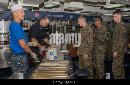 ATLANTIC OCEAN (Nov. 10, 2017) Airman Warreck Neubauer, from Fort Worth, Texas, and Culinary Specialist 2nd Class Tandy Hollingsworth, from Tulsa, Oklahoma, serve ice cream on the mess decks of the amphibious assault ship USS Iwo Jima (LHD 7) during the Marine Corps 242nd birthday dinner. Iwo Jima, components of the Iwo Jima Amphibious Ready Group and the 26th Marine Expeditionary Unit are conducting a Combined Composite Training Unit Exercise that is the culmination of training for the Navy-Marine Corps team and will certify them for deployment. (U.S. Navy photo by Mass Communication Speciali Stock Photo