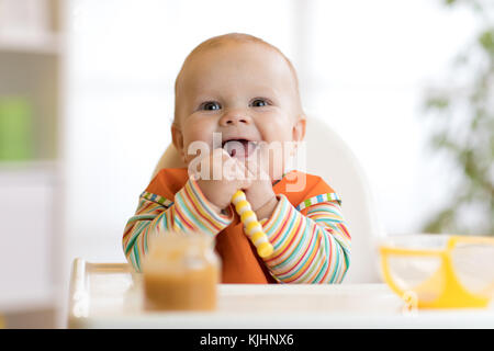 Happy infant baby boy spoon eats itself Stock Photo