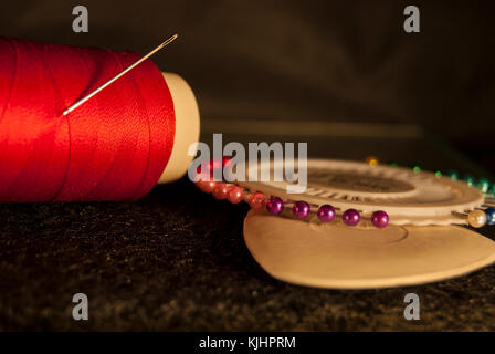 Set tailor: red thread with a needle, white chalk for drawing, a set of multicolored pins Stock Photo