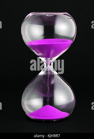 Close-up studio shot of an hourglass with purple sand pouring against white background for copy space Stock Photo