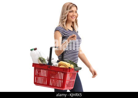 Young woman holding a shopping basket filled with groceries isolated on white background Stock Photo