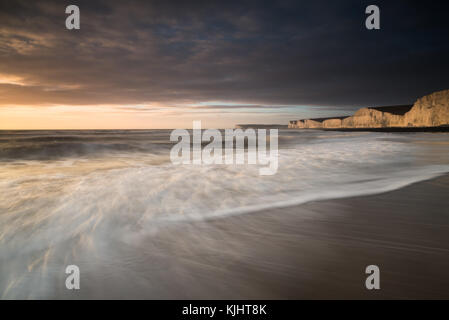 Birling Gap beach and the Seven Sisters white cliffs during sunset, warm light on chalk cliffs. Stock Photo