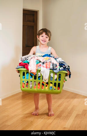Smiling Boy carrying laundry basket filled with clothes Stock Photo
