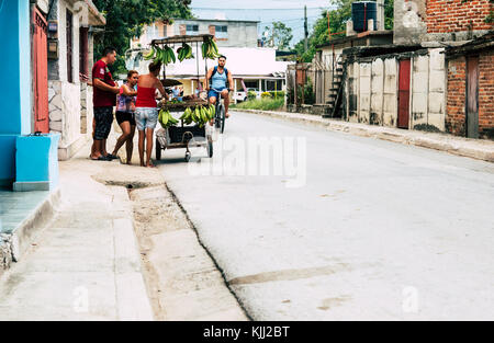 Las Tunas, Cuba - September 2017: People buying fruit. Man riding bicycle in background. Stock Photo