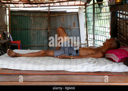 Old man lying on his bed in a shantytown. Battambang.  Cambodia. Stock Photo
