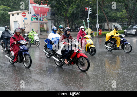 Heavy monsoon rain.  Vietnamese people driving Motorbikes on Saigon Street.  Ho Chi Minh City. Vietnam. Stock Photo