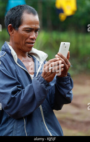 Jarai (Gia Rai) ethnic group.  Man using a smartphone.  Kon Tum. Vietnam. Stock Photo