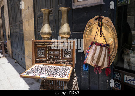 Old objects, souvenirs standing for sale outside an antiques shop in Old Cairo. Two brass vases and plate, a wooden Arabic table game and a sparto bag Stock Photo