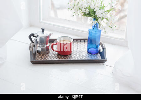 Coffee mug, coffee maker with vase of flowers on wooden tray on windowsill Stock Photo