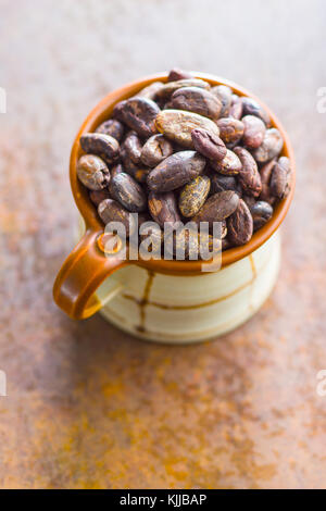 Dark cocoa beans in mug. Stock Photo