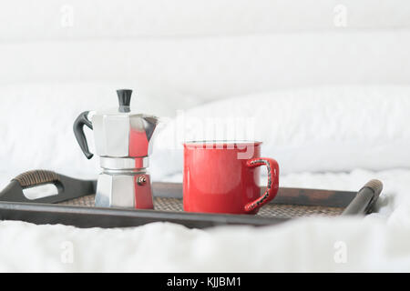 Red mug of coffee with steel coffee percolator on bed Stock Photo