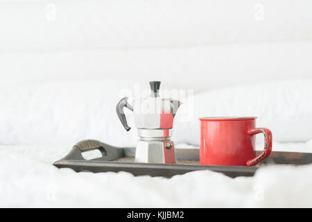 Coffee mug with coffee maker on wooden tray on bed Stock Photo