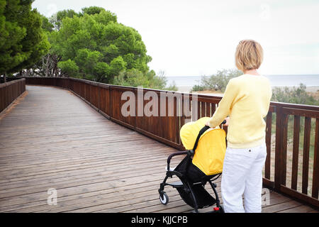 Blond hair woman strolling a baby in carriage Stock Photo