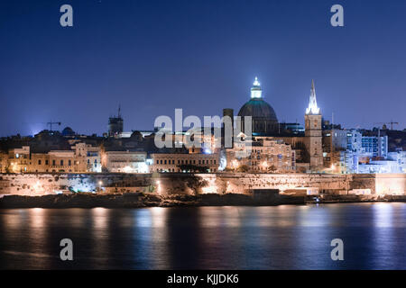 Malta's capital city Valletta, at night, from across the port in Sliema, with churches and buildings illuminated. Stock Photo