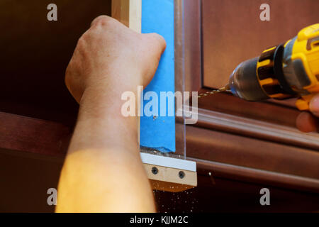 Installation of furniture hinges on the cabinet door master drills the door in the cabinet door Stock Photo