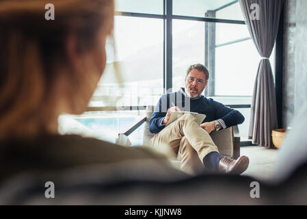 Psychologist listening to woman and taking down notes during therapy session. Psychotherapist understanding issues of a woman patient. Stock Photo