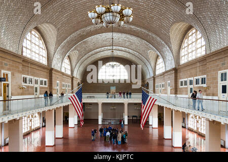 Ellis Island main hall with its barrel-vaulted ceiling, American flags, group of tourists, New York City, New York, NY, United States of America, USA.