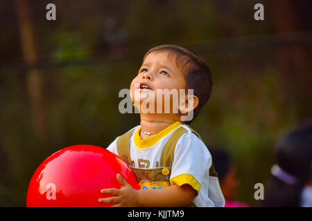 Cute Baby playing with red ball in the garden, Pune, Maharashtra. Stock Photo