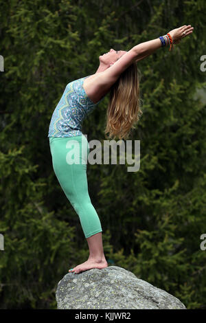 Woman practicing yoga on rocks. Les Contamines. France. Stock Photo