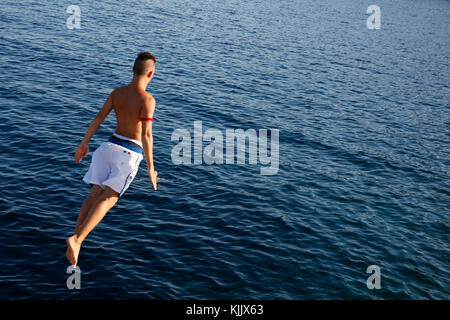 Young man jumping into the Med. Italy. Stock Photo