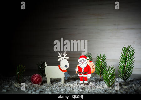 New Year's background. Figures of Santa Claus, deer and boy. Snow angel. Snowing. Night frame. Billet for postcards or congratulations. Copy space Stock Photo