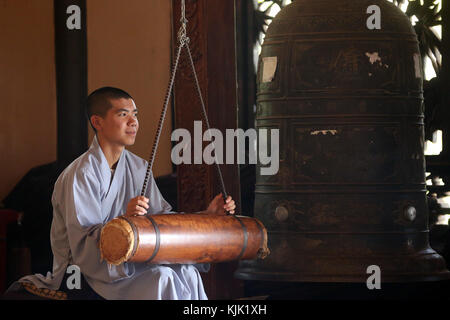 Linh An buddhist pagoda.  Young monk ringing bell in monastery.  Dalat. Vietnam. Stock Photo