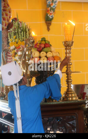 Cao Dai Holy See Temple.  High priest lighting candle on altar for  12 o'clock ritual.  Thay Ninh. Vietnam. Stock Photo