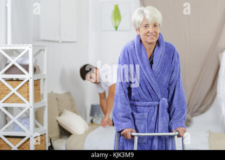 male nurse making bed while female senior using walker Stock Photo