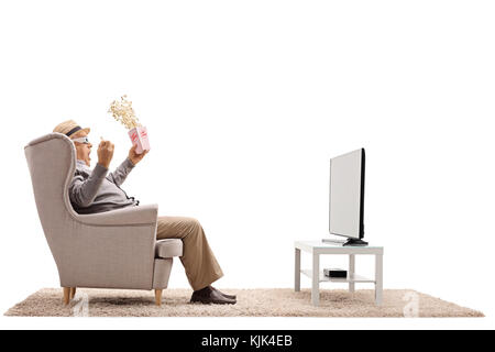 Terrified mature man with popcorn and 3D glasses sitting in an armchair and watching television isolated on white background Stock Photo
