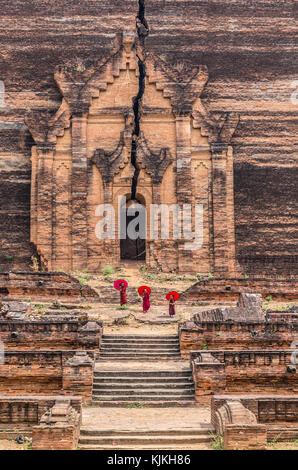 Three Buddhist novice are walking and holding the red umbrella at Mingun Pahtodawgyi, bagan, mandalay, myanmar Stock Photo