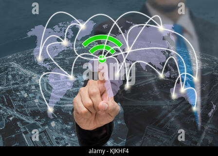 Businessman pointing or touching the wifi icon symbol on  over the top view of cityscape background and world map background which dicut each elements Stock Photo