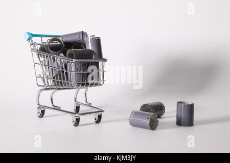 Shopping trolley and tangle of unrolled exposed 35mm film strips over a white background in a retro photography concept Stock Photo