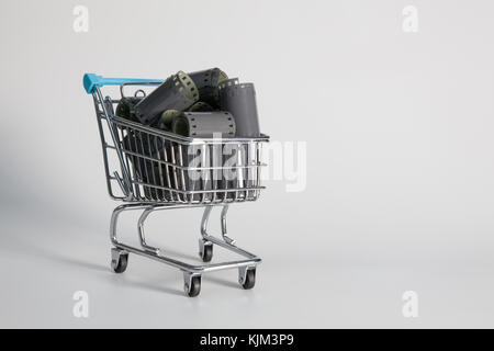 Shopping trolley and tangle of unrolled exposed 35mm film strips over a white background in a retro photography concept Stock Photo