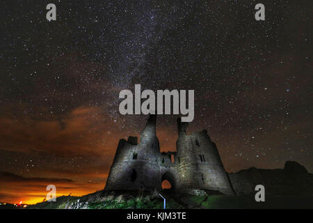 The great gatehouse of Dunstanburgh Castle ruins in Alnwick, Northumberland, under a starry sky. Stock Photo