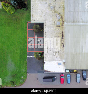 Cut vertical view from the air of an old, ugly tennis hall with parked cars in front of it, aerial view Stock Photo
