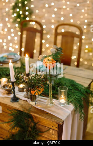decoration, table setting, floral design concept. on the edge of the table there are few posy composed of different leaves and wonderful roses that have colour of rising sun Stock Photo