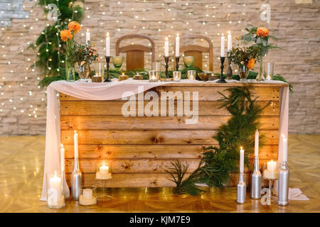 interior, holidays, engagement concept. furniture made of natural materials, used for celebration of wedding in the restaurant, it is surved for couple of lover and decorated with plants and candles Stock Photo