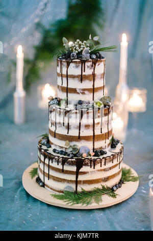 cooking, sweetness, wedding concept. close up of three tier amazing cake with white and brown streeps and chocolate frosting on the edges, decorated with flowers Stock Photo