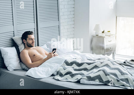 Pleasant good looking man using his smartphone Stock Photo
