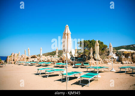 some sunloungers and umbrellas in a beach in Baja Sardinia, Sardinia, Italy Stock Photo