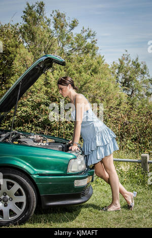 A beautiful young woman looking disappointed because her car has broken down. Stock Photo