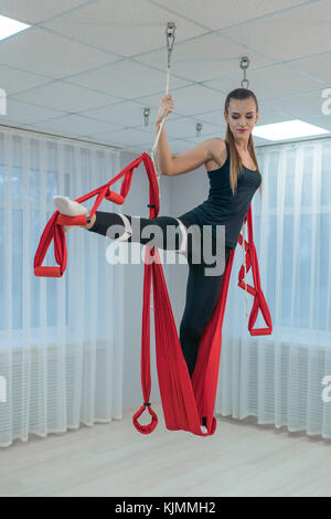 Fitness sports of air yoga. Beautiful young girl performs exercises of flying yoga Stock Photo