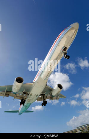 very low on final-approach to landing with cumulus clouds behind Stock Photo