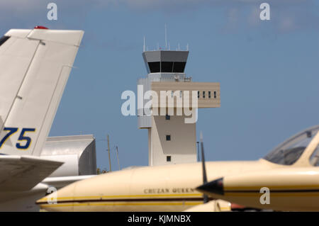 wing-tanks, propellers and nose of a Coastal Air Transport Cessna 402B and tail-fin of a Beech 99 with the air-traffic control-tower behind Stock Photo