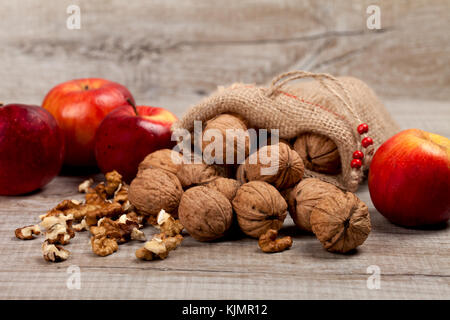 Whole walnuts, nut kernel and apples on a wooden table Stock Photo