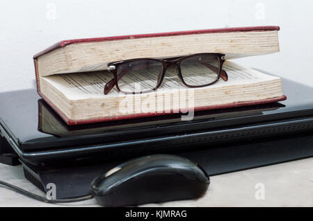 close-up of glasses placed inside a book and laid on laptop in the office Stock Photo